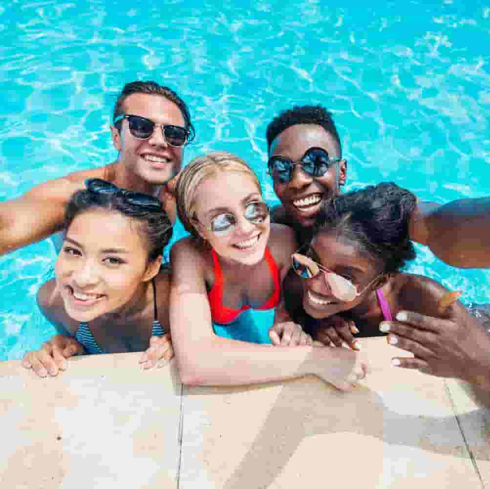 Group of friends in a pool smiling at the camera