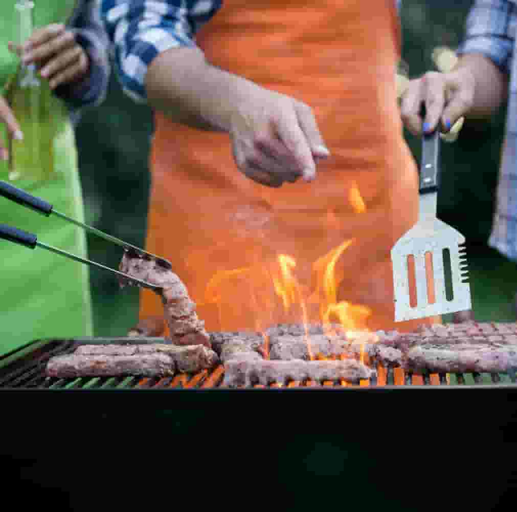 Small group grilling steaks over a fire